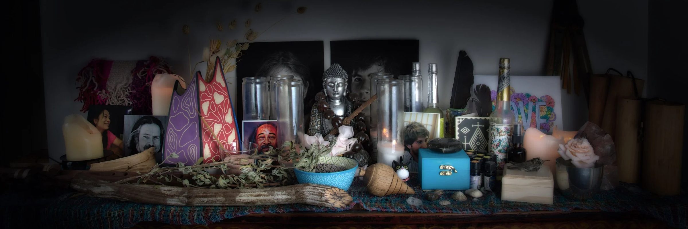 Michael’s ceremony altar: a Buddha figure, candles, feathers, dried sage, and photographs