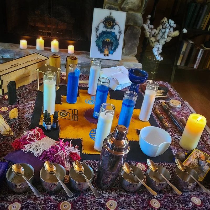 An altar with candles, crystals, bowls, and patterned cloth